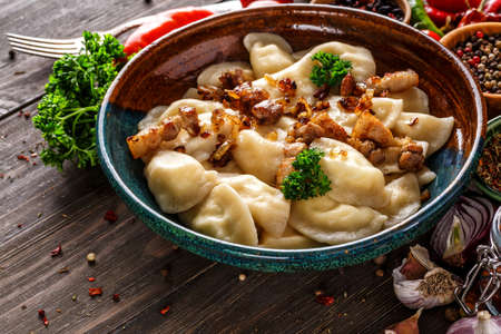 Pierogi or pyrohy, varenyky, vareniki, dumplings served with caramelized salted onion in bowl on wooden table - traditional Ukrainian foodの写真素材
