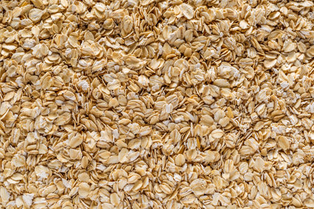 Background of oatmeal. Daylight. Throughout the frame are oatmeal flakes. Diet food concept. Top...