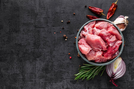 Shooting for the catalog. Bowl of chopped raw meat for a dog or cat on a rustic wood floor surrounded by fresh vegetables for a healthy animal dietの写真素材