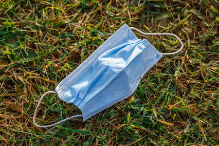 coronavirus COVID-19 pandemic.Medical face mask on the floor in the street.Used Surgical masks haphazardly strewn on pavement.Improperly discarding used face mask. Lost face mask at pavementの写真素材