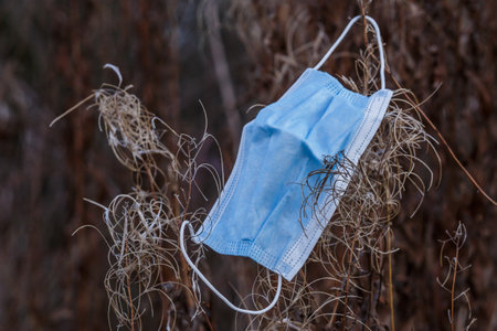 coronavirus COVID-19 pandemic.Medical face mask on the floor in the street.Used Surgical masks haphazardly strewn on pavement.Improperly discarding used face mask. Lost face mask at pavementの写真素材