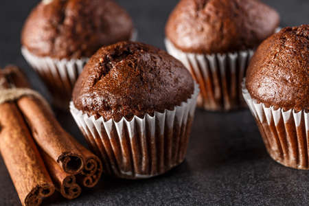 Chocolate cupcake with icing and chocolate bar in Dark lighting, Homemade delicious chocolate muffin on wooden background close-upの写真素材