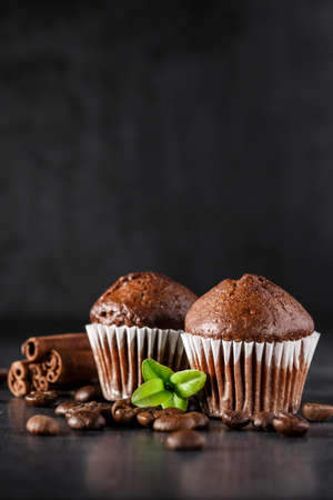 Chocolate cupcake with icing and chocolate bar in Dark lighting, Homemade delicious chocolate muffin on wooden background close-upの写真素材