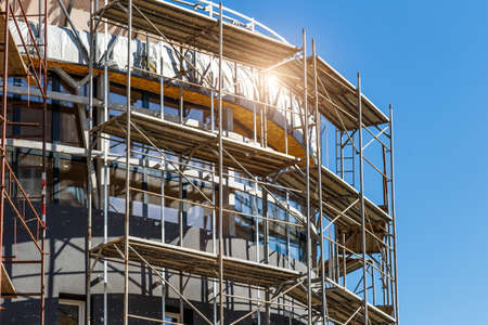 Extensive scaffolding providing platforms for work in progress on a new apartment block, Tall building under construction with scaffolds, Construction Site of New Buildingの写真素材