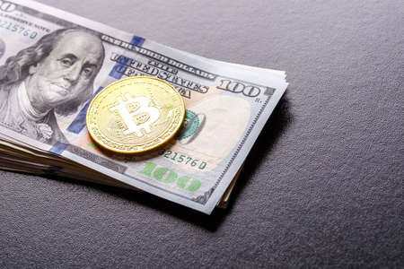 Golden Bitcoin lies on the banknotes.New virtual money. Crypto currency top view. Real coins of bitcoin on banknotes of one hundred dollars. Exchange, commercial. online business concept.の写真素材