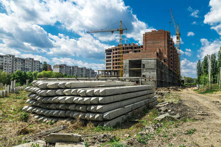Extensive scaffolding providing platforms for work in progress on a new apartment block, Tall building under construction with scaffolds, Freestanding tower crane on a building siteの写真素材