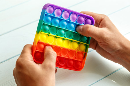 a man's hand presses on a colored rainbow silicone anti-stress toy pop it.Relaxation multicolored sensory pop it toy.New sensory antistress toy for children and adult.の写真素材