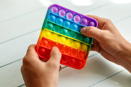 a man's hand presses on a colored rainbow silicone anti-stress toy pop it.Relaxation multicolored sensory pop it toy.New sensory antistress toy for children and adult.の写真素材
