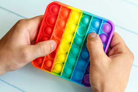 a man's hand presses on a colored rainbow silicone anti-stress toy popit.Relaxation multicolored sensory popit toy.New sensory anti stress toy for children and adult.の写真素材