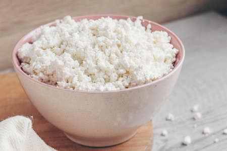 A large bowl of cottage cheese sits on a wooden chopping Board.の写真素材