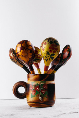 Russian wooden painted tableware: spoons in a mug on a light background. Preparations for the...