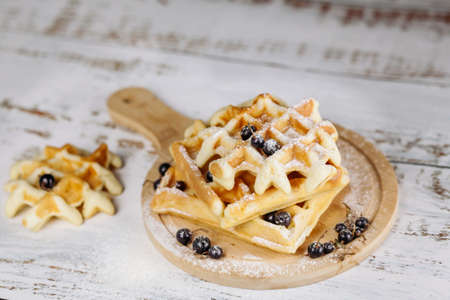 Viennese waffles are stacked on a black background, one on top of the other. Removed from the side. Golden waffles are decorated with black currants. At the top there is a place for the text.の写真素材