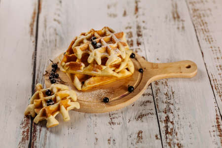 Viennese waffles are stacked on a black background, one on top of the other. Removed from the side. Golden waffles are decorated with black currants. At the top there is a place for the text.の写真素材