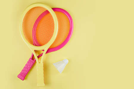 Shuttlecock and badminton rackets on a yellow background. Copy space for your text