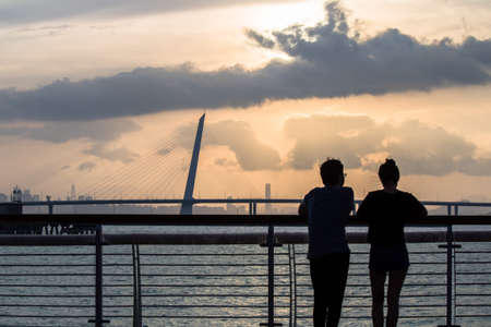 Couple watching sunrise in seashore park in shenzhenの写真素材