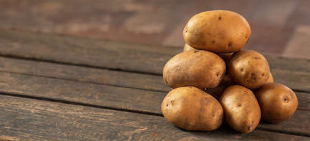 A pile of potatoes on the background of a wooden box. Concept: a bunch of potatoes, vegetable garden, farming, agricultureの写真素材