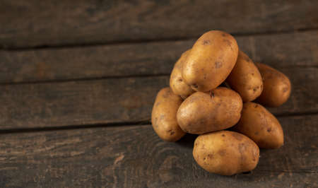 A pile of potatoes on the background of a wooden box. Concept: a bunch of potatoes, vegetable garden, farming, agricultureの写真素材