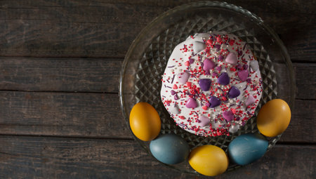 Easter cake in a transparent dish, around painted eggs in the colors of the flag of Ukraine. Yellow and blue (cyan). On wood texture. Concept: food, holiday, war in Ukraineの写真素材