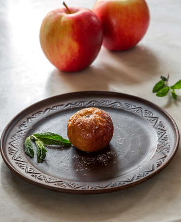 Baked apple on a brown plate with mint leaves and powdered sugarの写真素材