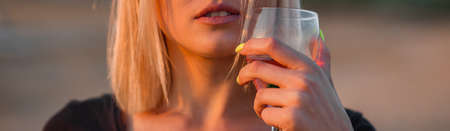 Girl blonde a glass of rose wine in her hands. Lips close up.の写真素材