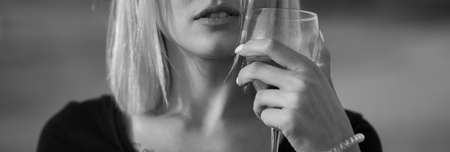 Girl blonde a glass of rose wine in her hands. Lips close up. black and white photoの写真素材