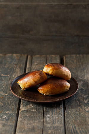 Baked pies on a clay plate on wooden boards. cookingの写真素材