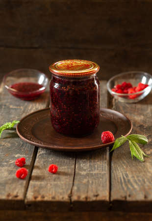 Closed jar of raspberry jam on wooden boards. Preservation, cooking, foodの写真素材
