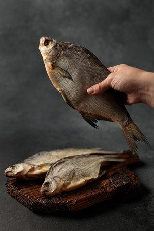 Dried fish breath in hand on black background