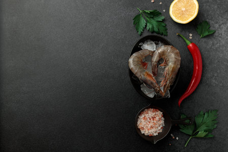 Large King prawns on lemon slices and ice. Hot peppers. Black plate. Black backgroundの写真素材
