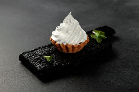 A sand basket with cream stands on a black wooden board on a gray background
