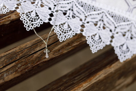 Silver Cross Necklace on Wooden Church Bench with Lace Clothの写真素材
