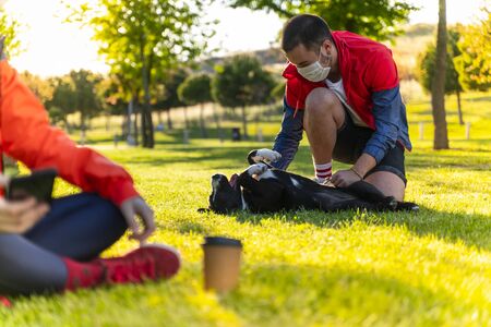 young couple wearing a protective mask is walking alone with a dog outdoors because of the corona virus pandemic covid-19の写真素材