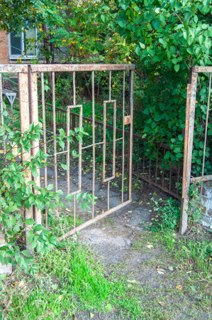 Metal fence of an old abandoned house with a gardenの写真素材