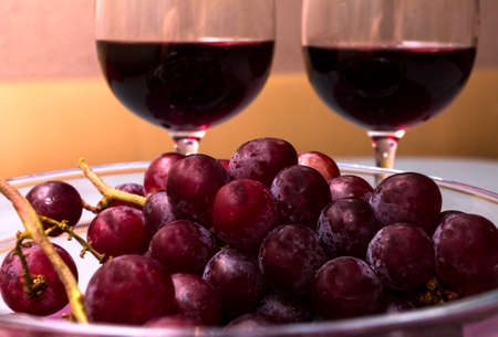 wine in the wine glass, grape in the vase on the table