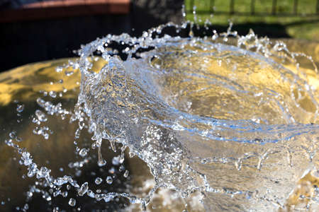 The child holds his hands under the water from the fountain の写真素材
