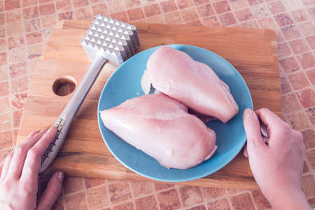 top view of process of cooking chicken breast in the kitchen with meat tenderizer hammer and knife の写真素材