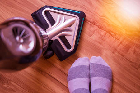 Using a modern actual wireless vacuum cleaner for cleaning the house with copy space