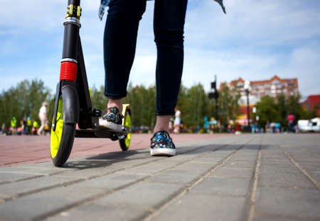 A girl with a kick scooter on the street. Copy space