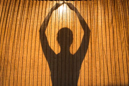 silhouette of girl holding the sun in her hands in yoga or meditation conceptの写真素材