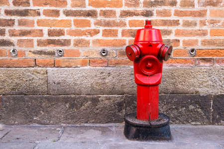 Red fire hydrant on the street on the brick wall background  の写真素材