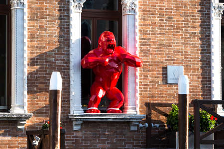 contemporary art: sculpture of a red monkey standing in a window at a canal in Venice, Italy 2017-08-22のeditorial素材