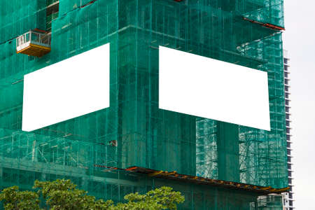blank mockup outdoor advertising with copy space on the wall of the building under construction with scaffoldingの写真素材