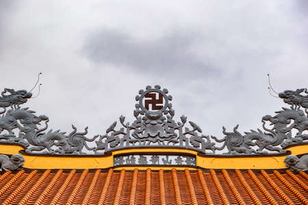 ancient religious icon swastika on the orange roof of the Buddhist pagoda 