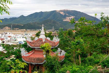 orange roof of the Buddhist pagoda with mountains and city on the background の写真素材