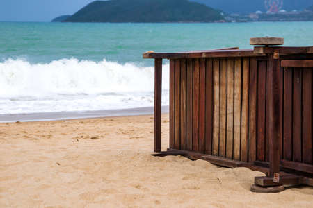 lonely sandy beach with beach chairs and umbrellas near the sea with big waves の写真素材