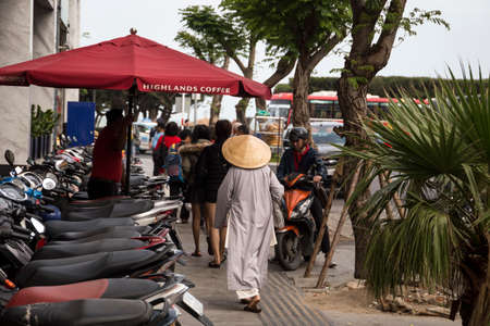 Vietnamese woman in traditional conical hat on street of the Nha Trang City in Vietnam 2018-01-10のeditorial素材