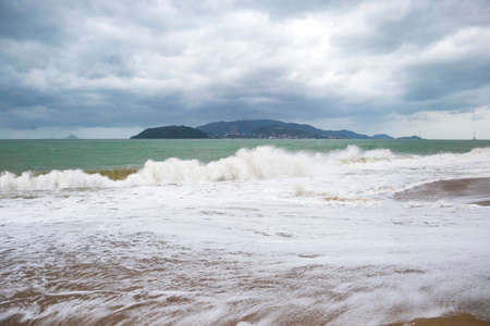 storm with big waves on the seashore with mountains on the background