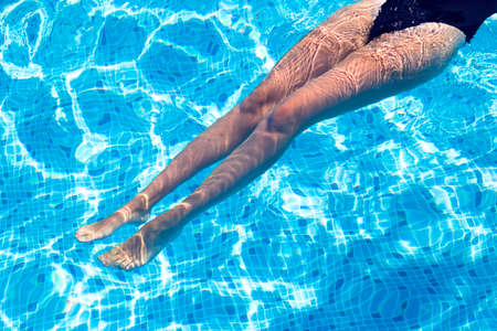 beautiful legs of a girl who rests in the swimming poolの写真素材