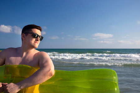 Men on the beach near the sea with swimming (Inflatable air) mattress