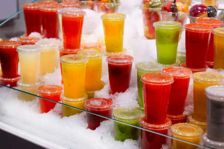 showcase with different types of colorful cold juice and smoothie in the ice.の写真素材